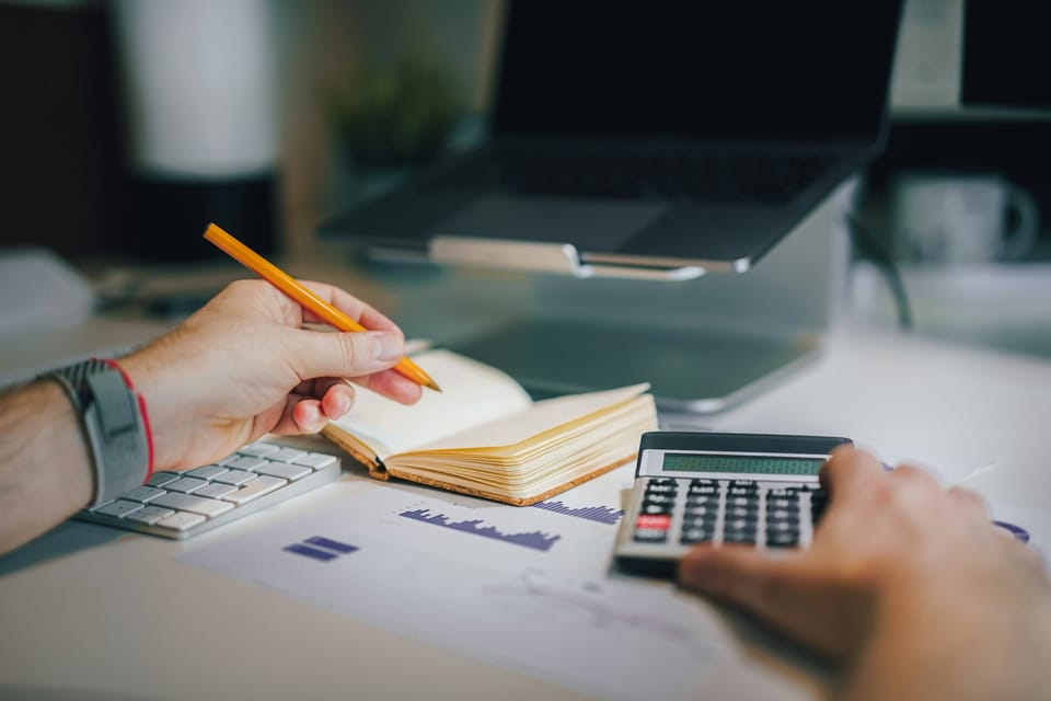 Person writing beside a calculator